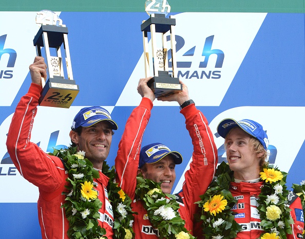 (From L) Australia's Mark Webber, Germany's Timo Bernhard and  New Zealand's Brendon Hartley, drivers of the Porsche 919 - Hybrid N°17, celebrate with their second place with trophies  on the podium of the 83rd Le Mans 24 Hours endurance race on June 14, 2015 in Le Mans, western France. AFP PHOTO / JEAN-FRANCOIS MONIER        (Photo credit should read JEAN-FRANCOIS MONIER/AFP/Getty Images)